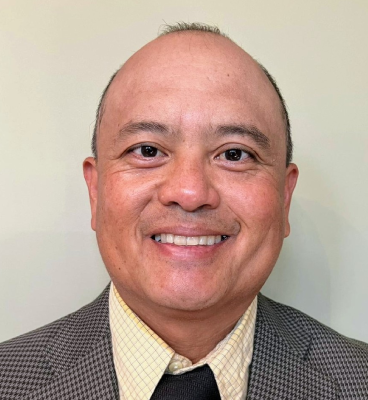 A man in a suit and tie smiling for the camera.